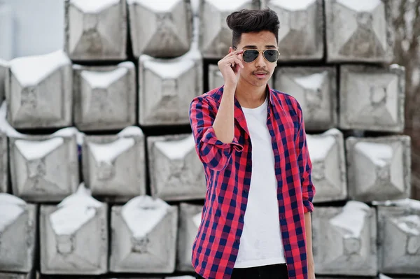格子縞のシャツとサングラスでカジュアルな若いインド人は石のブロックに対して提起 — ストック写真