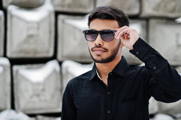 黒いシャツとサングラスでカジュアルな若いインド人は石のブロックに対して提起 — ストック写真