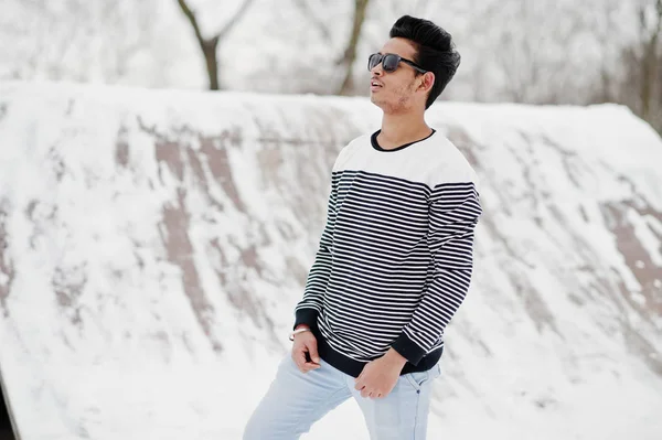 Casual young indian man in sunglasses posed at winter day.