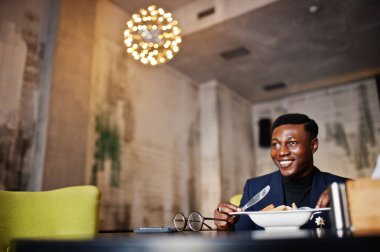 Kafede oturan ve salata yemek takım elbiseli şık Afrikalı-Amerikalı adam.