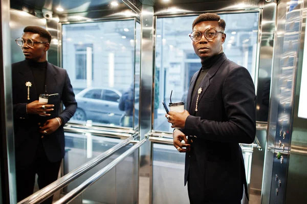 スーツと携帯電話 エレベーター内部脅威の手でコーヒー カップを持つガラスでおしゃれなアフリカ系アメリカ人 — ストック写真