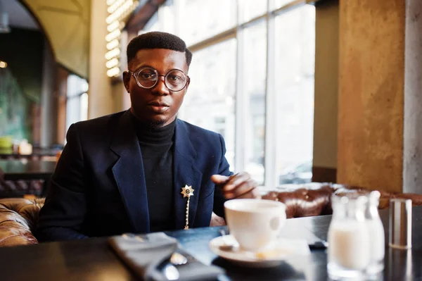 スーツとグラス一杯のコーヒーでカフェに座ってファッショナブルなアフリカ系アメリカ人 — ストック写真