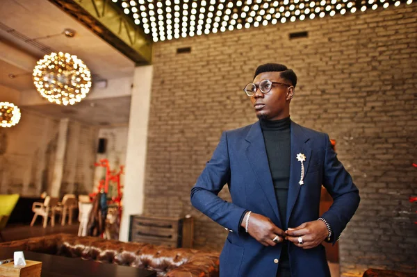 Fashionable african american man in suit and glasses posed at cafe.