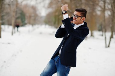 Takım elbise ve kış günü açık ve cep telefonu, konuşan, poz gözlük şık Hint öğrenci adama mutlu duygular göster.