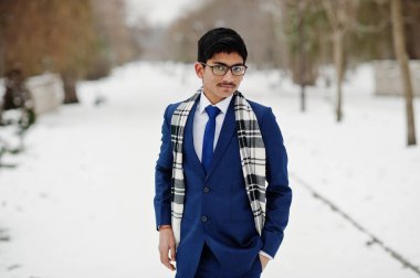 Şık Hint öğrenci erkek takım elbise, gözlük ve eşarp kış gününde açık poz verdi..