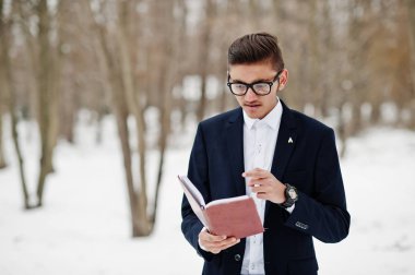 Şık Hint öğrenci erkek takım elbise ve gözlük kış günü açık elinde defter ile poz verdi.