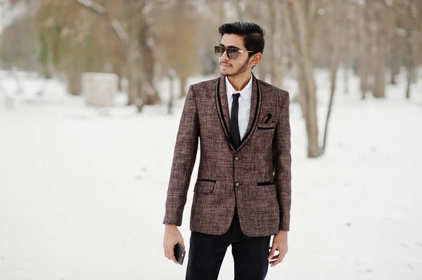 Stylish indian student man in brown suit and sunglasses posed at winter day outdoor.