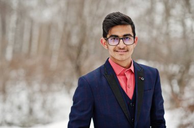 Şık Hint öğrenci erkek takım elbise ve gözlük kış günü açık poz verdi..