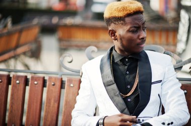 Şık Afro-Amerikan yakışıklı bankta oturan beyaz takım.