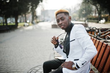 Şık Afro-Amerikan yakışıklı bankta oturan beyaz takım.