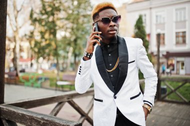 Cep telefonu el ile beyaz elbiseli şık Afro-Amerikan yakışıklı.