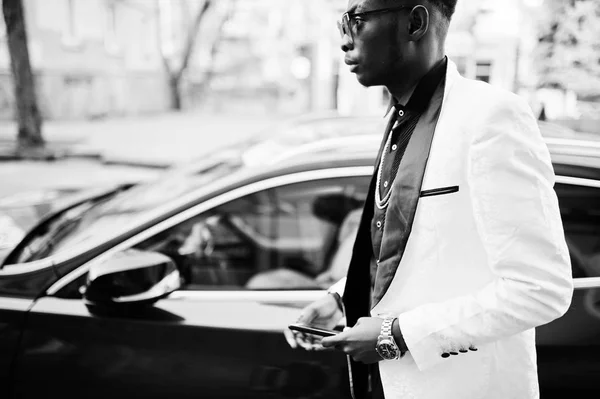 手元の携帯電話で赤い高級車に対して白いスーツでシックなハンサムなアフリカ系アメリカ人 — ストック写真