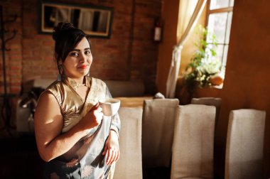 Zarif esmer Güney Asya Hint kızı sari kapalı Cafe ve çay içme poz verdi.