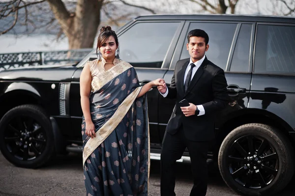 エレガントでファッショナブルなインドの友人サリーの女は スーツを着た男のカップルは 豊かな黒の Suv 車に対して提起 — ストック写真