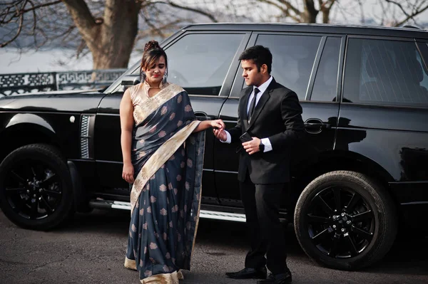 エレガントでファッショナブルなインドの友人サリーの女は スーツを着た男のカップルは 豊かな黒の Suv 車に対して提起 — ストック写真