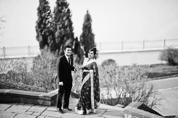 サリーの女は スーツを着た男のエレガントでファッショナブルなインドの友人カップル湖に対して階段でポーズをとった — ストック写真