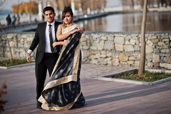 Elegant and fashionable indian friends couple of woman in saree and man in suit dancing together outdoor.
