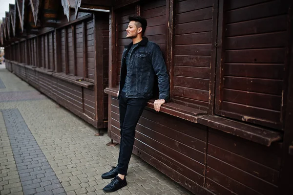 Handsome and fashionable indian man in black jeans jacket posed outdoor.