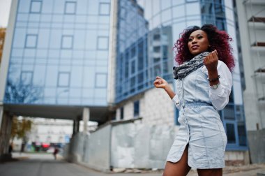 Modern çok öykülü bina karşı yöneltilen kot pantolon içinde çekici kıvırcık Afrikalı-Amerikalı kadın.