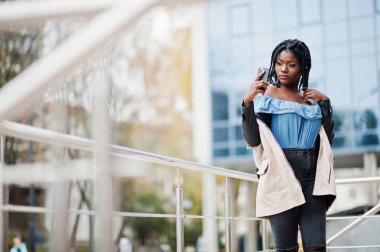 Modern çok öykülü bina selfie cep telefonu yapma karşı parmaklıklar yakınındaki çekici Afrikalı-Amerikalı kadın ceket dreads ile poz verdi.