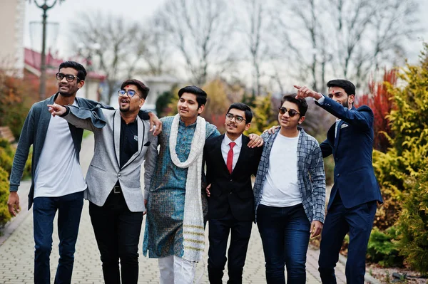 Group of six south asian indian mans in traditional, casual and business wear walking and shows fingers to something.