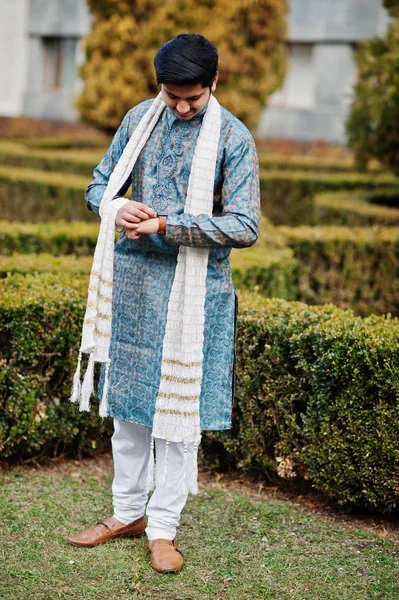 伝統的な服に白いスカーフでインド人摩耗脅威に対して彼の時計を見て 公園で緑の茂み屋外 — ストック写真