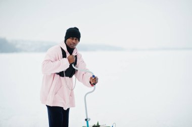 Afro-Amerikan balıkçı delik matkap tarafından donmuş buz yapma. Balık tutma kış.