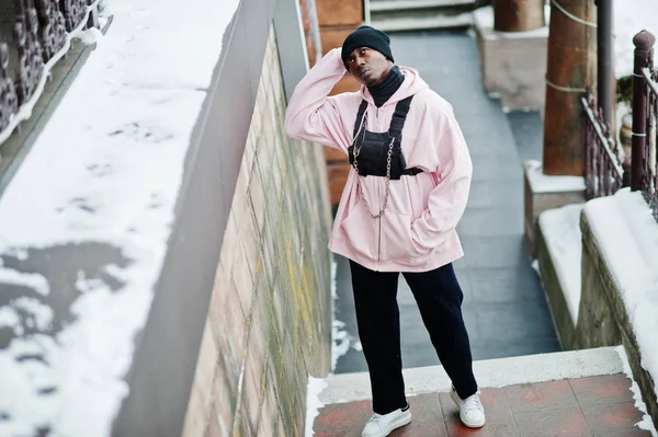 Pembe Kapşonlu şık kentsel tarzı Afrikalı-Amerikalı adam kış gününde poz verdi..
