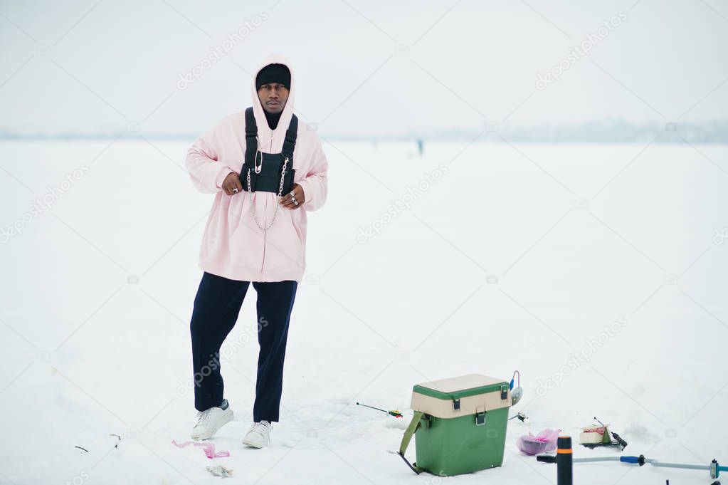 African american fisherman on frozen sea. Winter fishing.