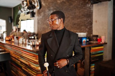 Zarif siyah ceket ve gözlük, holding retro baston baston şişesi veya altın elmas topu saplı tippling kamışı olarak şık Afro-Amerikan beyefendi. Zengin moda afro adam.