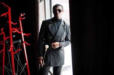 Zarif siyah ceket ve güneş gözlüğü, holding retro baston baston şişesi veya altın elmas topu saplı tippling kamışı olarak şık Afro-Amerikan beyefendi. Zengin moda afro adam.