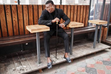 Zarif siyah ceket, holding retro baston baston şişesi veya altın elmas topu saplı tippling kamışı olarak şık Afro-Amerikan beyefendi. Zengin moda afro adam.