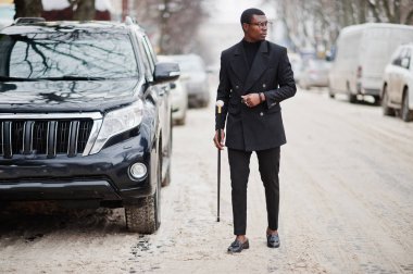 Zarif siyah ceket, holding retro baston baston şişesi veya altın elmas topu saplı tippling kamışı olarak şık Afro-Amerikan beyefendi. Zengin moda afro insan iş suv araba karşı.