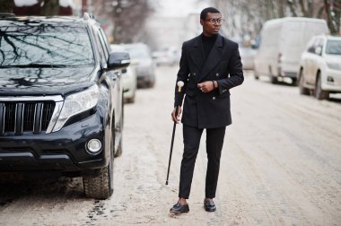 Zarif siyah ceket, holding retro baston baston şişesi veya altın elmas topu saplı tippling kamışı olarak şık Afro-Amerikan beyefendi. Zengin moda afro insan iş suv araba karşı.