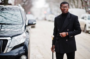 Zarif siyah ceket, holding retro baston baston şişesi veya altın elmas topu saplı tippling kamışı olarak şık Afro-Amerikan beyefendi. Zengin moda afro insan iş suv araba karşı.