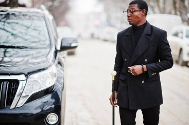 Zarif siyah ceket, holding retro baston baston şişesi veya altın elmas topu saplı tippling kamışı olarak şık Afro-Amerikan beyefendi. Zengin moda afro insan iş suv araba karşı.