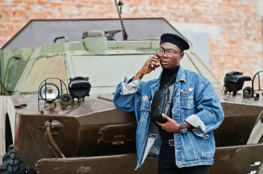 Btr askeri zırhlı araç karşı telefonda konuşan Afro-Amerikan erkek kot ceket, bere ve gözlük,.