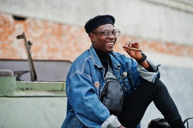 Puro sigara ve btr askeri zırhlı araç karşı yöneltilen Afro-Amerikan erkek kot ceket, bere ve gözlük,.