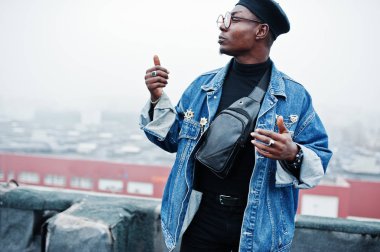 Afro-Amerikan erkek kot ceket, bere ve terk edilmiş çatı üzerinde yarattığı gözlük.