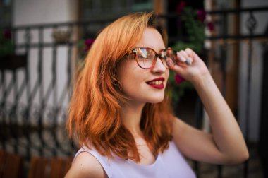 Bahar şehir Caddesi'nde poz gözlük kadında çekici redhaired.