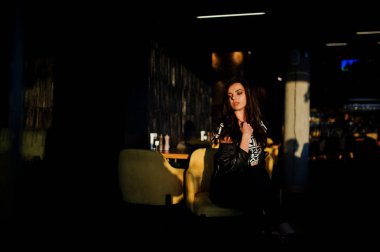 Bir barda deri ceketli genç kıvırcık kadın.