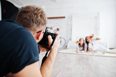 Kim pizza yemek studio ikiz kızlar üzerinde çekim adam fotoğrafçı. İş profesyonel fotoğrafçı.