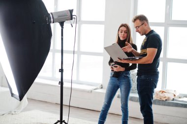 Fotoğrafçı asistanı stüdyoda çekim hakkında açıklama ve laptop arıyorum. Takım çalışması ve beyin fırtınası.