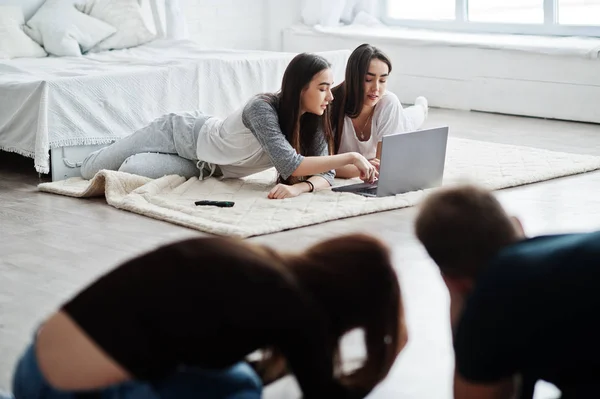 The team of two photographers shooting on studio at knees two twins models who are looking at the laptop. Professional photographer on work. Master class.