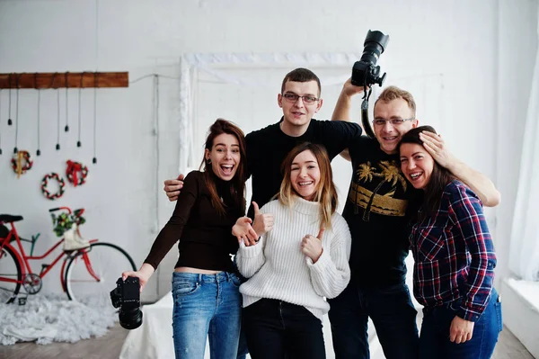 Group of five peoples, friends photographers and designers on studio shooting after hard work day. They happy and laughing.