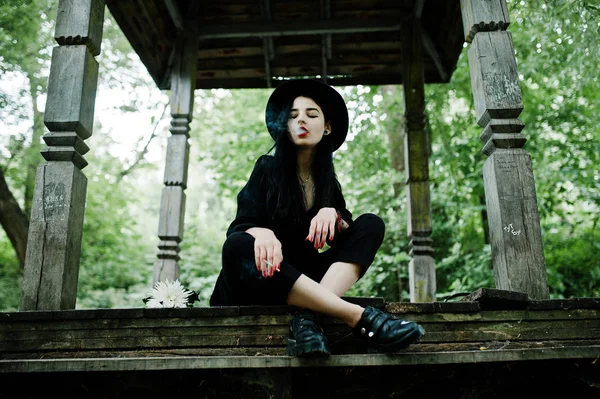 Sensual smoker girl all in black, red lips and hat. Goth dramatic woman smoking thin cigarette.