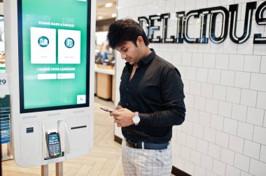 Hintli müşteri mağazasında sipariş ve kendi ödeme kat kiosk ödeme terminal hızlı yemeğe para. Onun cep telefonu arıyorum. Dil seçimi ekranında olun.