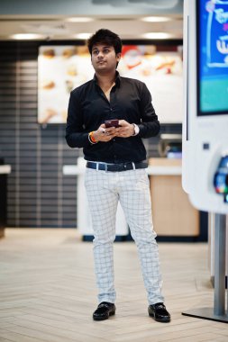 Şık Hintli adam kendini ödeme kat kiosk cep telefonu el ile fast food café de poz verdi.