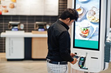 Hintli müşteri mağazasında sipariş ve kendi ödeme kat kiosk aracılığıyla cep telefonu üzerinde temassız kredi kartıyla ödeme terminal hızlı yemeğe para. Pass ödemek.