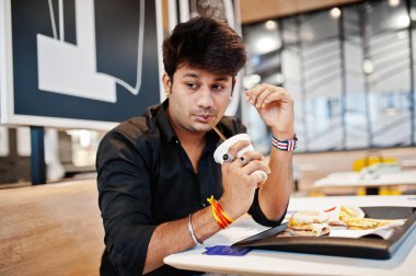 Fast food Cafe ve içecek soda oturan şık Hintli adam.